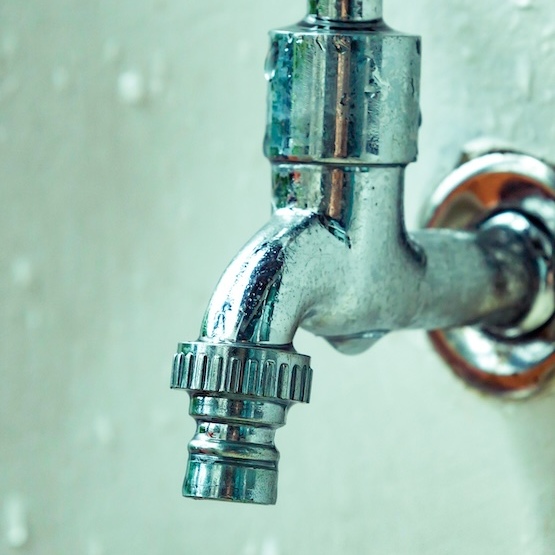 A chrome water faucet with an off-white background.