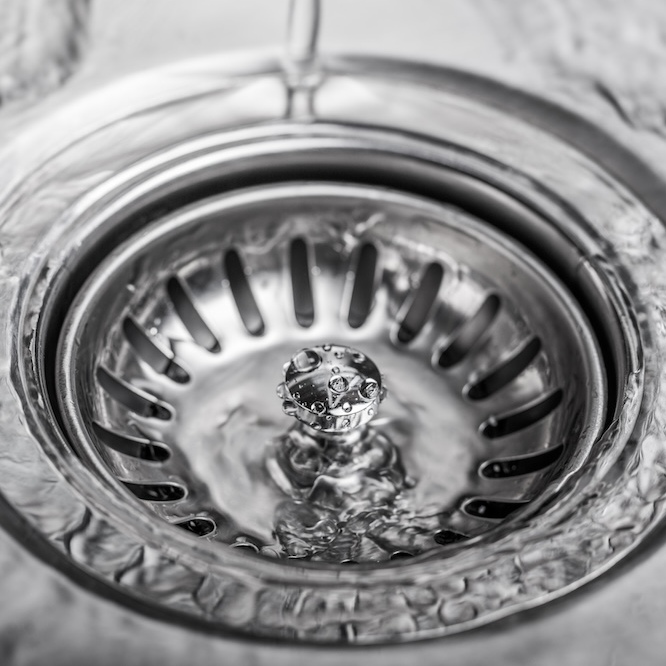 A garbage disposal with water running over it from a faucet (not pictured.)