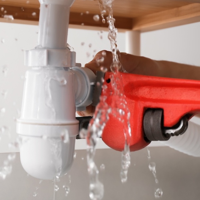 Wrench being used to tighten a leaking pipe connection.